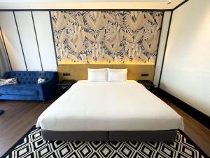 Bangi Resort Hotel في بانغي: غرفة نوم بسرير ابيض كبير واريكة زرقاء