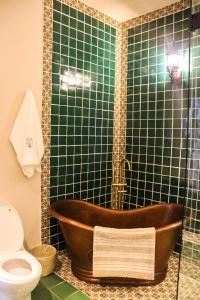 a bathroom with a wooden tub in a green tiled shower at Hotel Boutique Gloriagave in Tequila