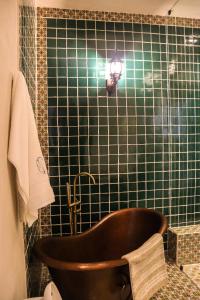 a bath tub in a bathroom with a green tiled wall at Hotel Boutique Gloriagave in Tequila