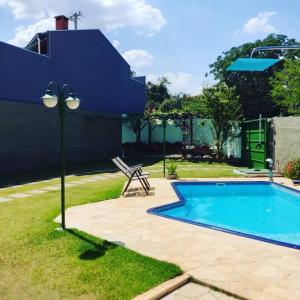 a blue swimming pool with a bench and a light pole at Casa dos Villares in Águas de São Pedro