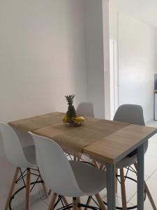 een houten tafel met stoelen en een ananas erop bij Studio La Caféière in Saint-Claude