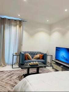 ein Wohnzimmer mit einem blauen Sofa und einem TV in der Unterkunft Incredible 2 Bedroom Space Available in Accra