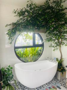 uma casa de banho com uma banheira branca e um espelho redondo em N&D Happy House- Studio Apartment - Phong tieu chuan khach san, bep nau va nha ve sinh trong khuon vien em Hanói