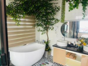 La salle de bains est pourvue d'une grande baignoire et d'un arbre. dans l'établissement N&D Happy House- Studio Apartment - Phong tieu chuan khach san, bep nau va nha ve sinh trong khuon vien, à Hanoï