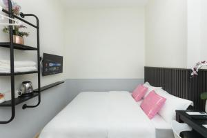 a bedroom with a white bed with pink pillows at Hotel Luma Senawang in Seremban