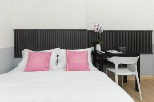 um quarto com uma cama com almofadas cor-de-rosa e uma secretária em Hotel Luma Senawang em Seremban