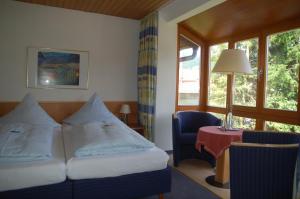 a hotel room with a bed and a table and a window at Hotel Garni Otto Huber in Oberammergau