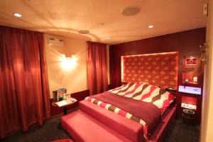 a bedroom with a large bed with a red headboard at ROOM Ryugasaki in Ushiku