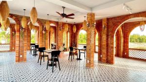 a dining room with tables and chairs and brick walls at Somo Farm Cửu Long in Vĩnh Long