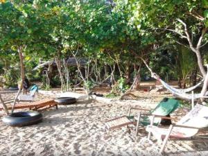eine Hängematte und Stühle am Strand mit Bäumen in der Unterkunft Room in Bungalow - Foresta Cottage of Koh Pu in Ko Jum