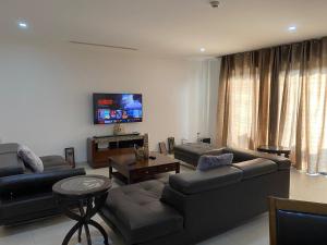 a living room with couches and a flat screen tv at Elegant 3 Bedroom Space Available in Accra