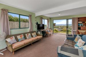 een woonkamer met een bank en een tv bij The Mermaid's Rest - Whatuwhiwhi Holiday Home in Kaitaia