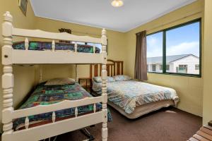 two bunk beds in a room with a window at The Mermaid's Rest - Whatuwhiwhi Holiday Home in Kaitaia