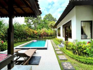 une arrière-cour avec une piscine et une maison dans l'établissement Sari Kembang villa ubud, à Ubud