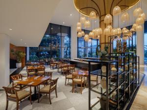 a restaurant with tables and chairs and windows at Luminor Hotel Padjadjaran Bogor by WH in Bogor