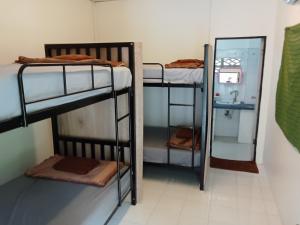 a room with three bunk beds and a mirror at Tiki Tribe Bar & Hostel in Koh Tao