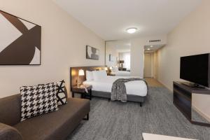 a hotel room with a bed and a couch at Punthill Norwest in Baulkham Hills