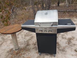 einen Grill und eine Holzbank neben einem Tisch in der Unterkunft Eureka Station Camping Retreat in Apple Tree Creek