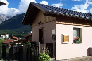 una pequeña casa con una valla negra delante de ella en Fabbricato Indipendente Centro, en Lozzo Cadore