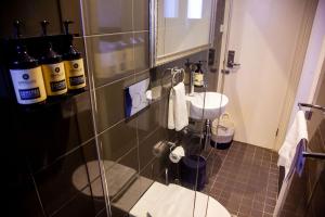 a bathroom with a sink and some bottles on the wall at Bayswater Boutique Lodge in Sydney