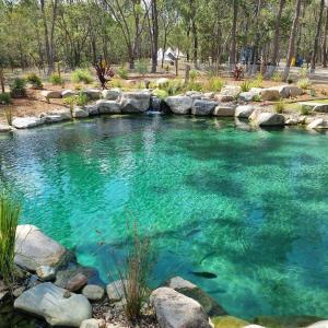 una piscina de agua turquesa con rocas en un jardín en Eureka Station Camping Retreat, en Apple Tree Creek