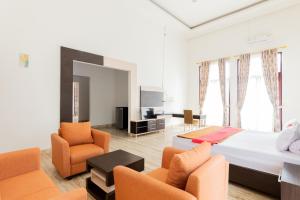 a bedroom with a bed and two chairs and a television at RedDoorz Premium @ Gandaria Jagakarsa in Jakarta