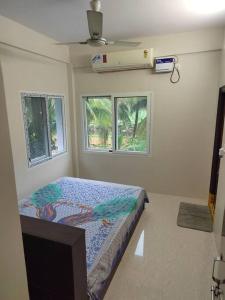 um quarto com uma cama num quarto com duas janelas em Gangi Kota North Flat em Kovvūr