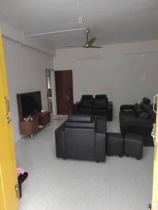 sala de estar con muebles negros y TV de pantalla plana en Gangi Kota North Flat en Kovvūr