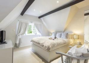 a bedroom with a white bed and a window at Culls Cottage, in Southrop