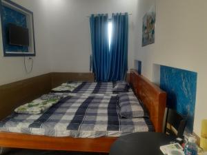a bedroom with a bed with a blue curtain at Ha Na Đức Linh 