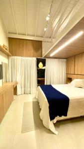 een slaapkamer met een groot bed en een blauwe deken bij Praia do Forte: apto studio com mezanino in Mata de Sao Joao