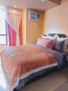 a bedroom with a bed with pink pillows and a window at Congressional Town Center in Manila