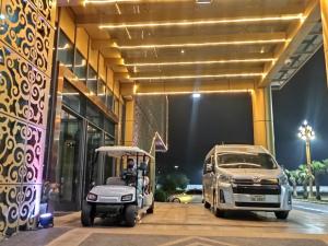 ST Vegas Hotel في Ban Nong-Heo: سيارة قولف متوقفة خارج مبنى مع سيارة