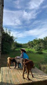 CROSSROADS HAVEN FARM في Majayjay: رجل وثلاث كلاب على سطح خشبي