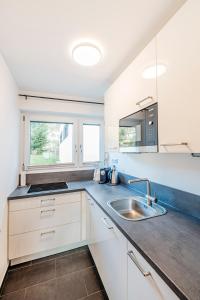 een keuken met witte kasten en een wastafel bij Ferienwohnung Michael - ruhig gelegen und nah am See in Schliersee