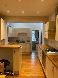 cocina con armarios blancos y suelo de madera en Delightful Victorian House en Mánchester