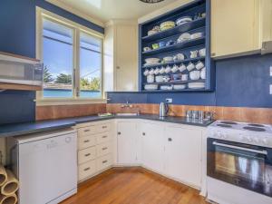 a kitchen with white cabinets and blue walls at Beachhouse View in Riverton