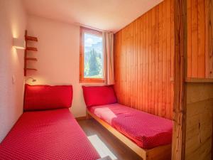 ヴァルモレルにあるAppartement Valmorel, 1 pièce, 4 personnes - FR-1-356-322の赤いベッド2台と窓が備わる小さな客室です。