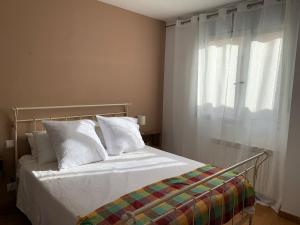 ein Schlafzimmer mit einem Bett mit weißen Kissen und einem Fenster in der Unterkunft Apartamento con jardín en Costa Quebrada in Liencres