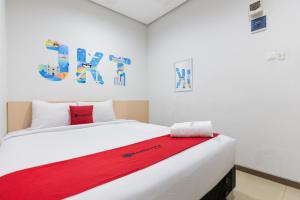 um quarto com uma cama com um cobertor vermelho em RedDoorz Plus Syariah near Mall Pondok Indah em Jakarta