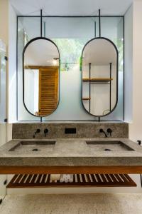 a bathroom with two sinks and two mirrors at Terra Resort in Ahangama