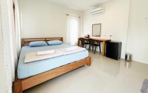a bedroom with a bed and a table and a desk at ครูหนูบ้านพัก แหลมงอบ Krunou baanpak in Trat