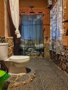 baño con aseo y cortina de ducha con la torre Eiffel en Junia Guesthouse Bukit Lawang, en Bukit Lawang