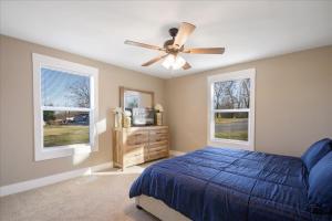 a bedroom with a blue bed and a ceiling fan at • Maverick House • Downtown Siloam Springs in Siloam Springs