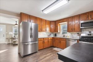 uma cozinha com armários de madeira e um frigorífico de aço inoxidável em • Maverick House • Downtown Siloam Springs em Siloam Springs