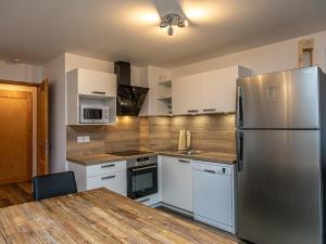 a kitchen with a stainless steel refrigerator and white cabinets at Chalet Plagne Soleil, 4 pièces, 8 personnes - FR-1-351-83 in Plagne Villages