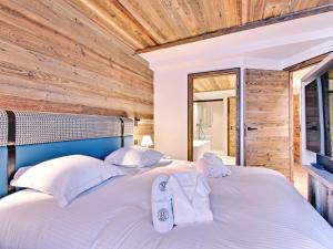 a bedroom with a large white bed with wooden walls at Appartement de luxe avec sauna, ski aux pieds à Méribel - FR-1-613-21 in Méribel