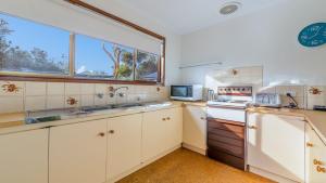a kitchen with white cabinets and a window at Pescarina Free Wifi Netflix in Inverloch