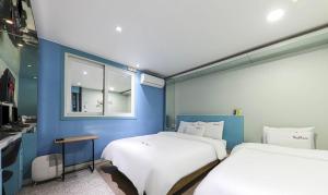 twee bedden in een kamer met een blauwe muur bij 9 to 9 motel in Gimhae