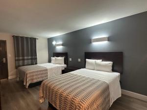 a hotel room with two beds with white sheets at Hotel Casa by Arya in Carrollton